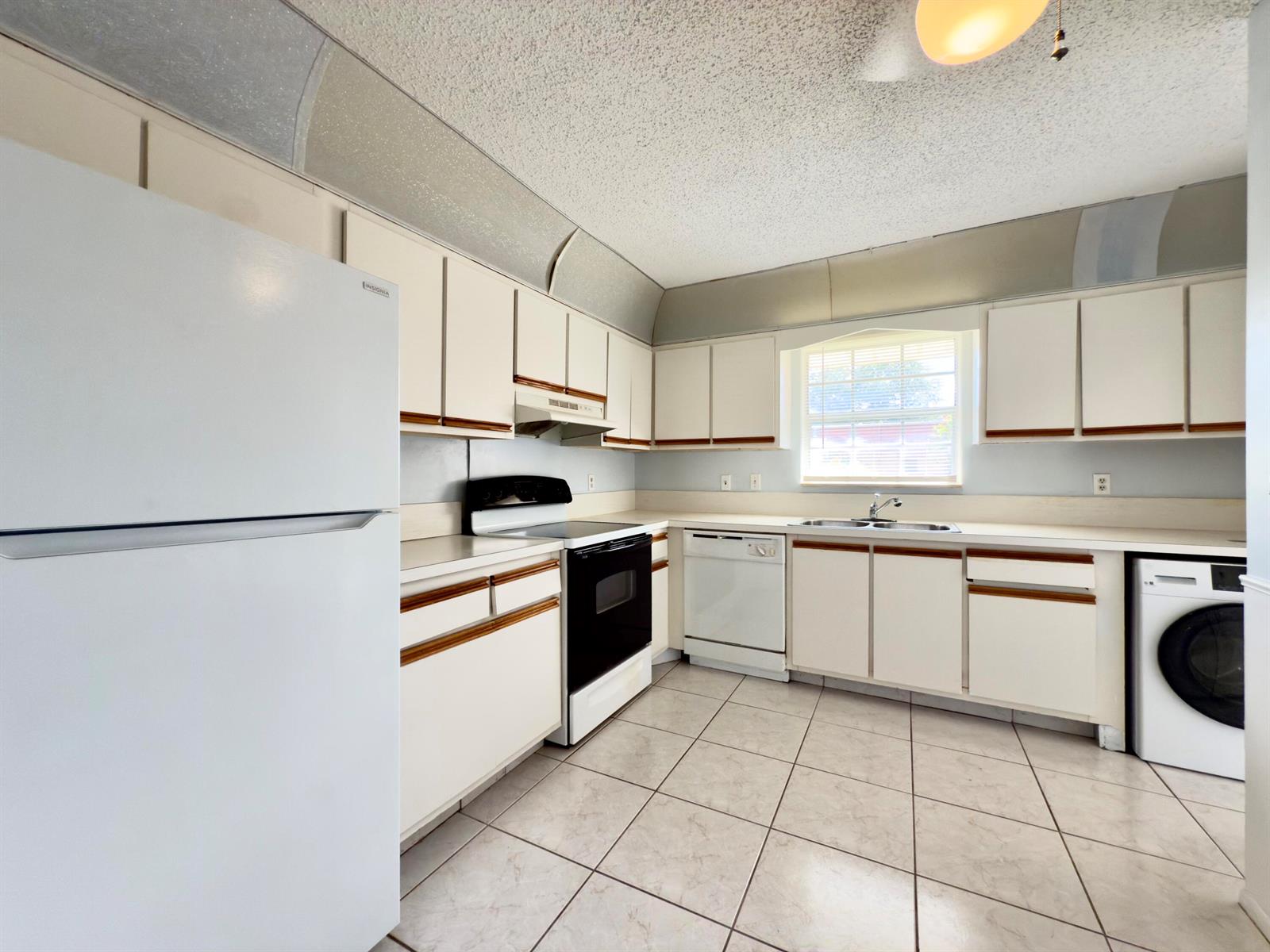 A kitchen features white cabinets, a black stove, a dishwasher, and a white washing machine — 170 Amherst Lane, Lake Worth FL 33467, LAKE WORTH, FL