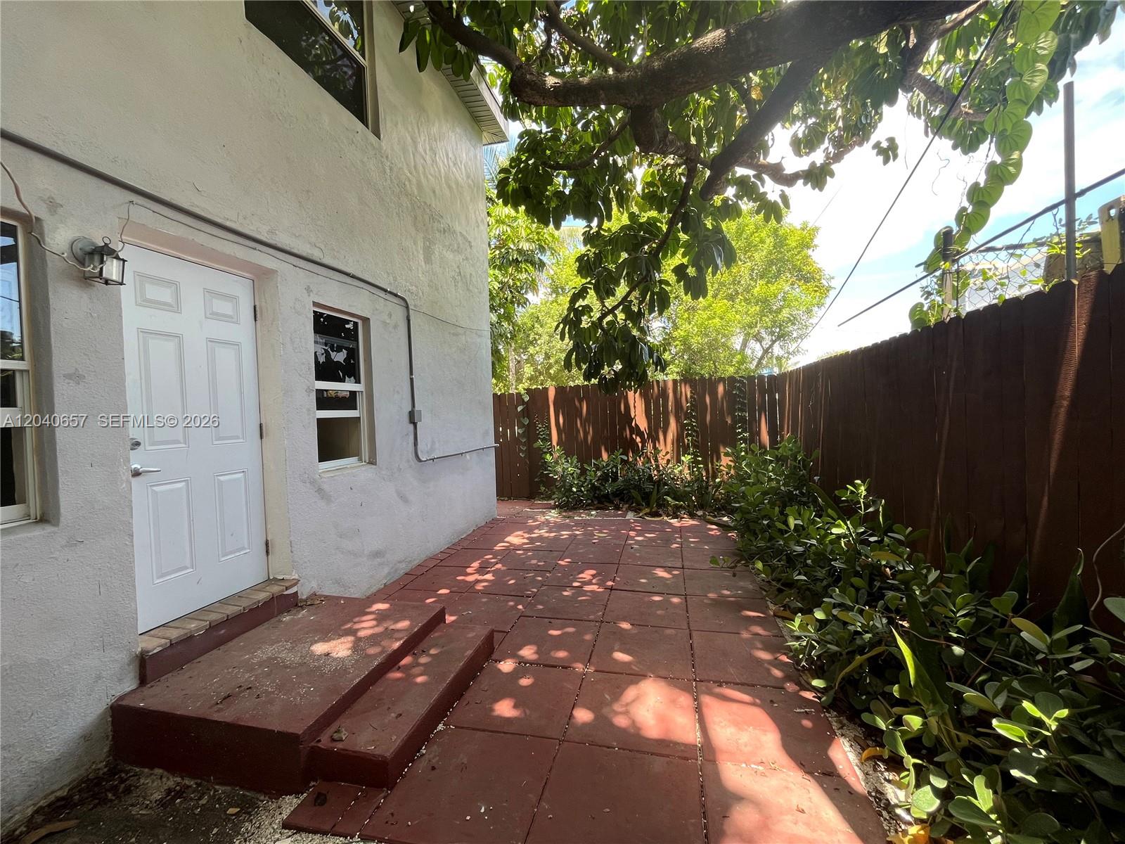 A white building exterior features a red-tiled patio, a white door, and a wooden fence — 820 SW 31st Ave, Miami FL 33135, MIAMI, FL