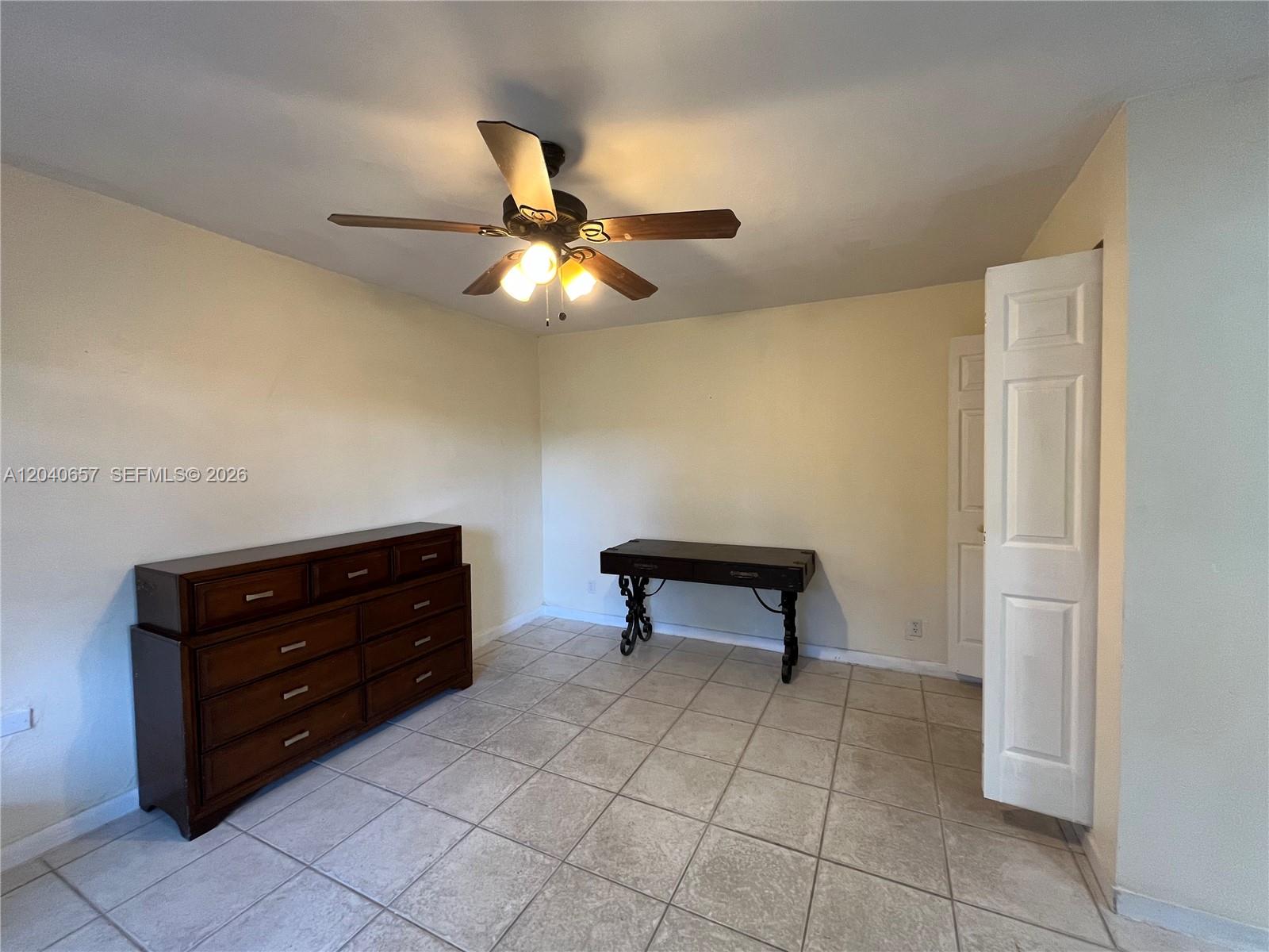 A bedroom features a wooden dresser, a small desk, a ceiling fan, and tiled flooring — 820 SW 31st Ave, Miami FL 33135, MIAMI, FL
