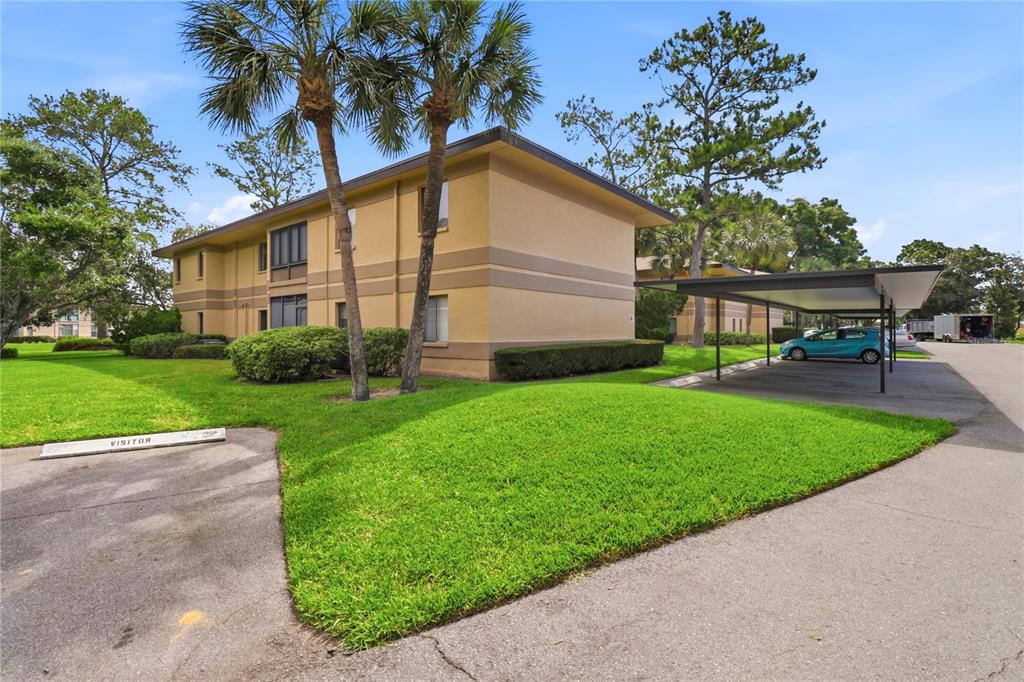A two-story apartment building with a covered parking area and a grassy lawn — 2685 SABAL SPRINGS CIRCLE UNIT 105, CLEARWATER, FL