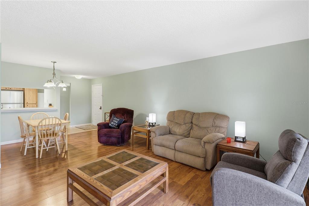 A living room and dining area with hardwood floors, light green walls, and furniture — 2685 SABAL SPRINGS CIRCLE UNIT 105, CLEARWATER, FL