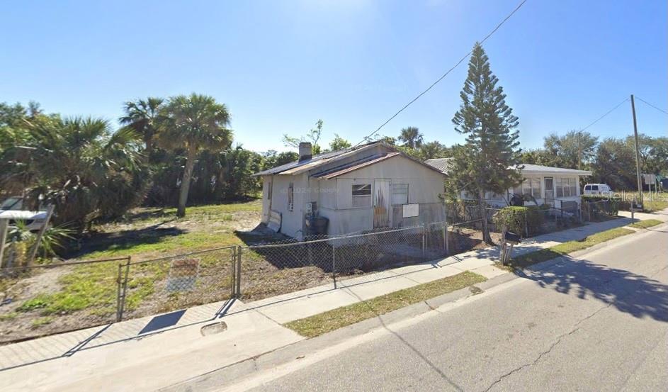 A small, weathered single-story house sits on a grassy lot behind a chain-link fence — 314 AVENUE Y NE, WINTER HAVEN, FL