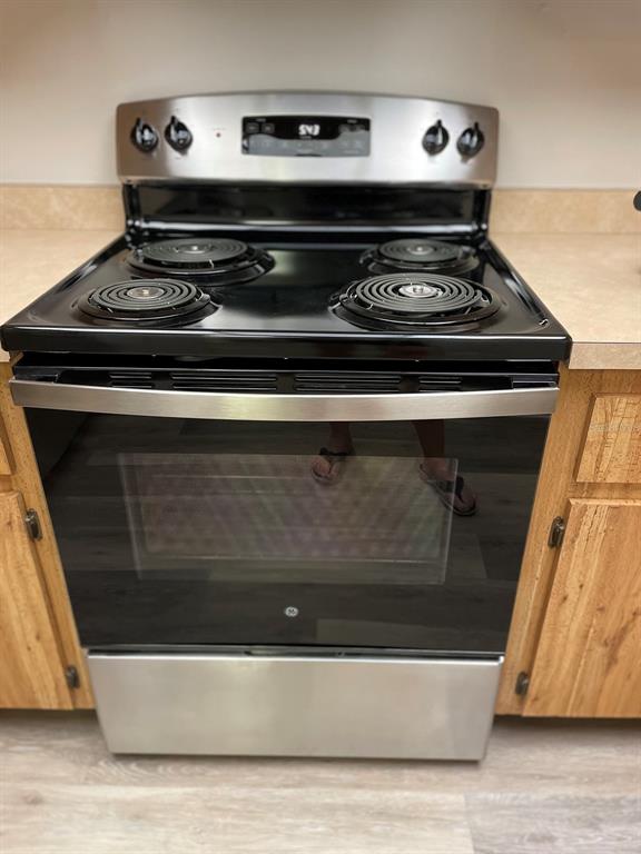 A stainless steel GE electric range is positioned between wooden kitchen cabinets — 3610 54TH STREET W UNIT B8, BRADENTON, FL