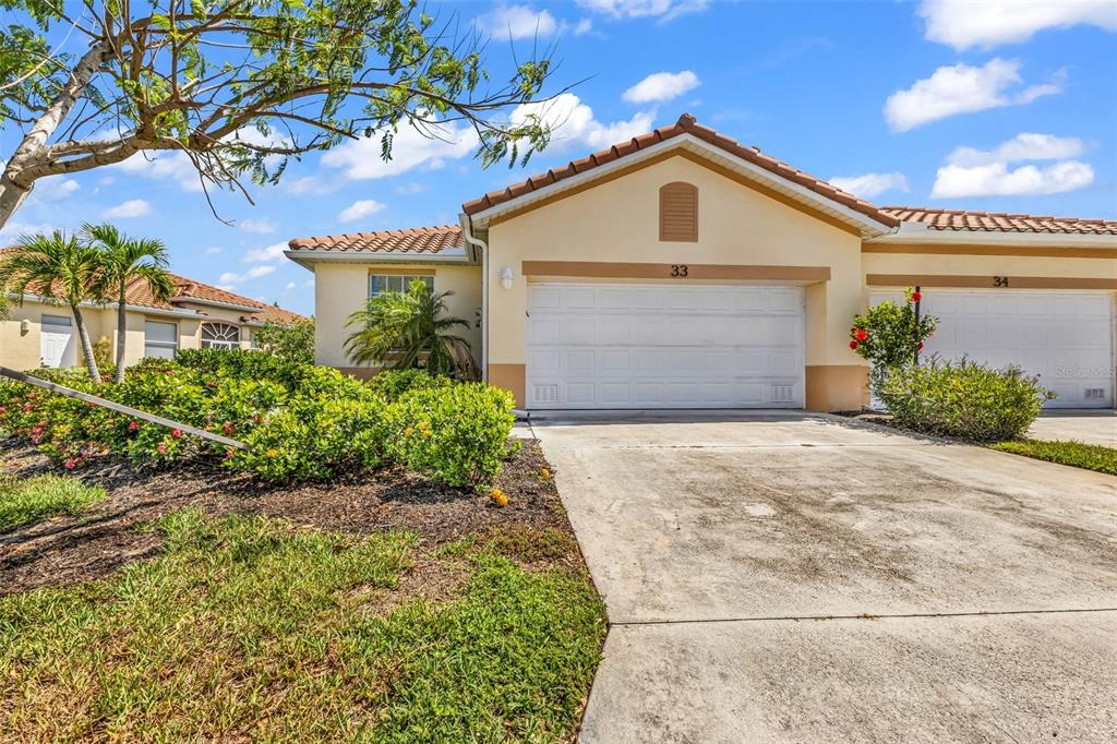 A beige single-story house with a white garage door and a concrete driveway — 3181 MATECUMBE KEY ROAD UNIT 33, PUNTA GORDA, FL