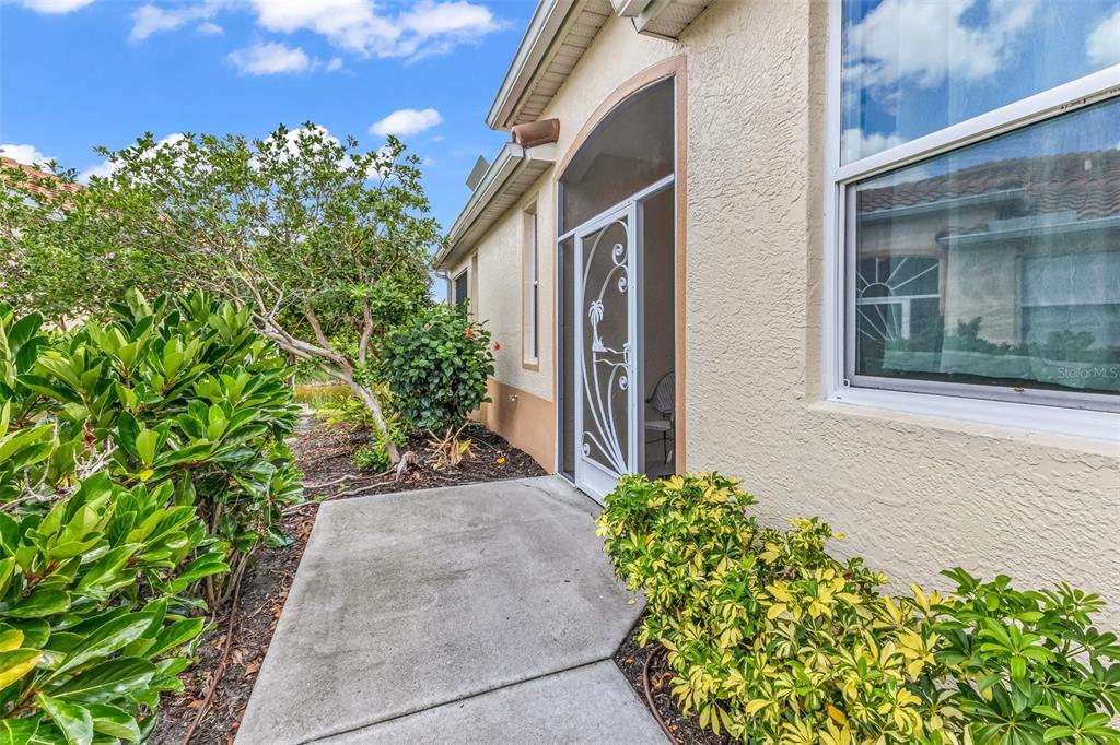 A concrete walkway leads to a white decorative screen door on the side of a house — 3181 MATECUMBE KEY ROAD UNIT 33, PUNTA GORDA, FL