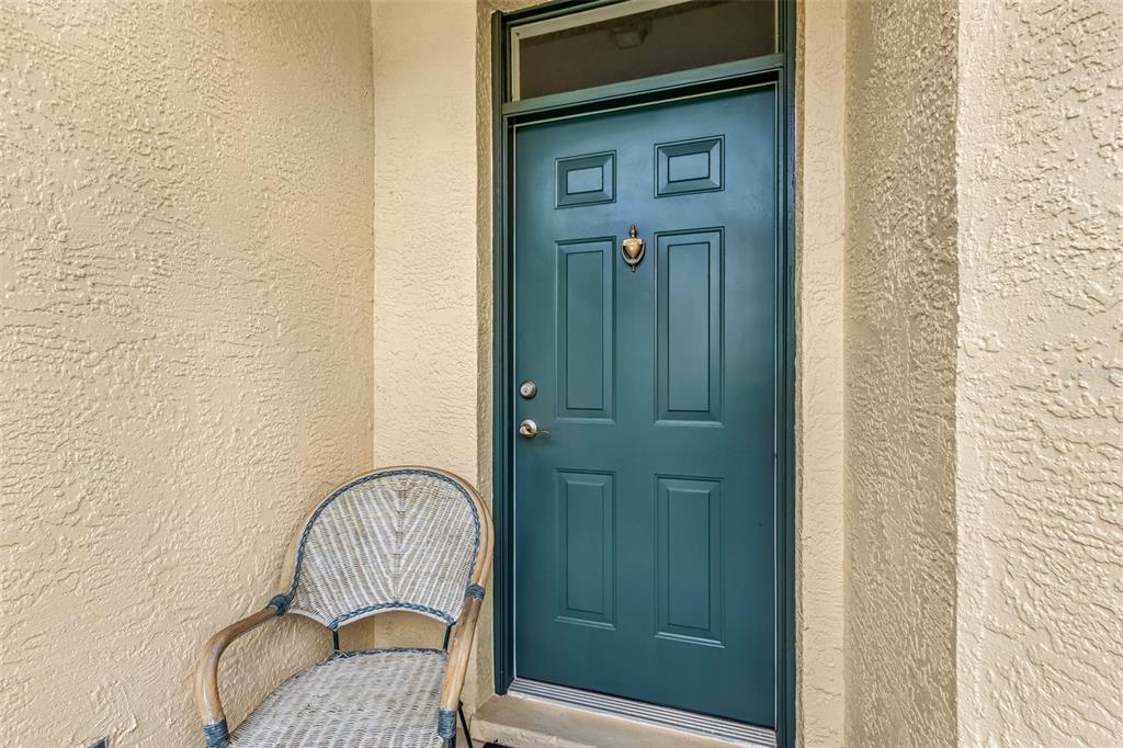 A teal front door with a brass knocker sits next to a wicker chair — 3181 MATECUMBE KEY ROAD UNIT 33, PUNTA GORDA, FL