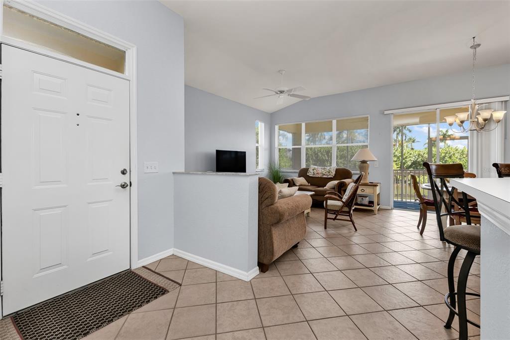 An open-concept living and dining area features tile flooring, light blue walls, and sliding doors — 3181 MATECUMBE KEY ROAD UNIT 33, PUNTA GORDA, FL
