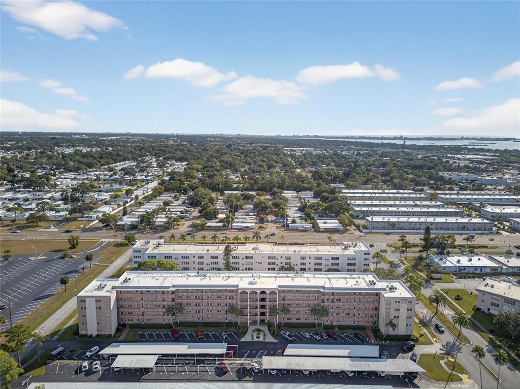 An aerial view shows a multi-story apartment building with a parking lot and covered carports — 5521 80TH STREET N UNIT 511, ST PETERSBURG, FL