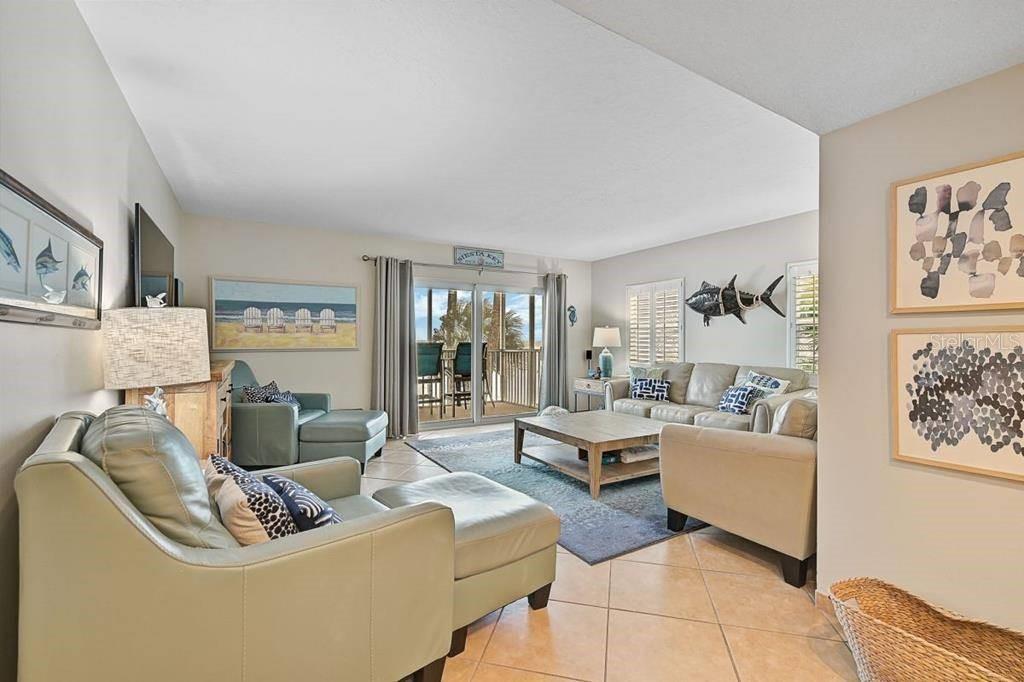 A living room features light-colored sofas, a wooden coffee table, and a sliding glass door — 6154 MIDNIGHT PASS ROAD UNIT 206, SARASOTA, FL