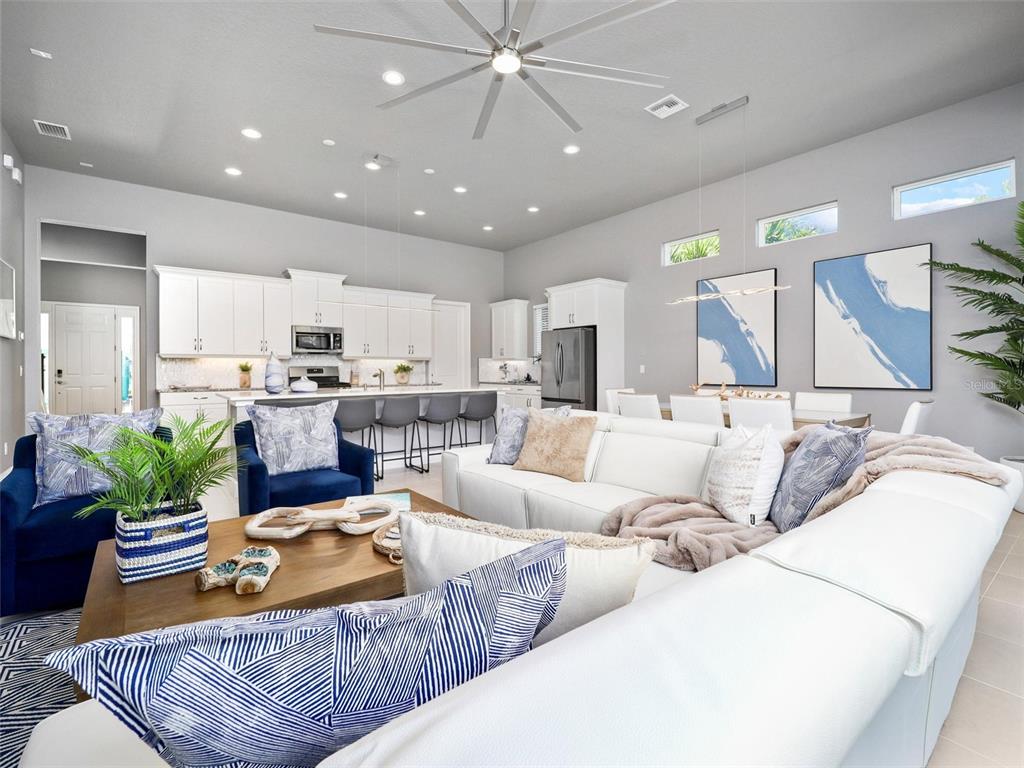 A bright, open-concept living room and kitchen featuring white cabinetry, a large sectional, and artwork — 55 ATLANTIC DRIVE, PALM COAST, FL