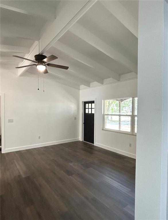 A living room with vaulted beamed ceilings, dark wood-look flooring, and a black front door — 34798 EVERGREEN WAY, DADE CITY, FL