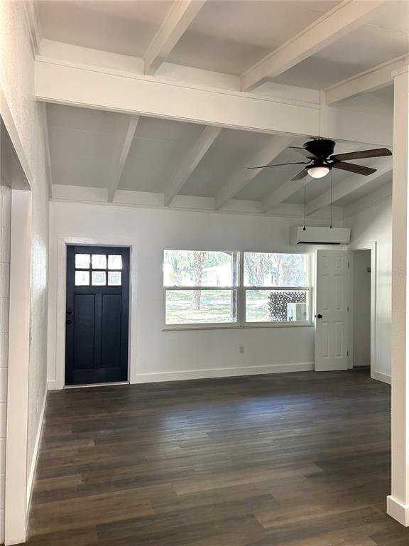 A living room features white vaulted ceilings with exposed beams, dark flooring, and a black door — 34798 EVERGREEN WAY, DADE CITY, FL