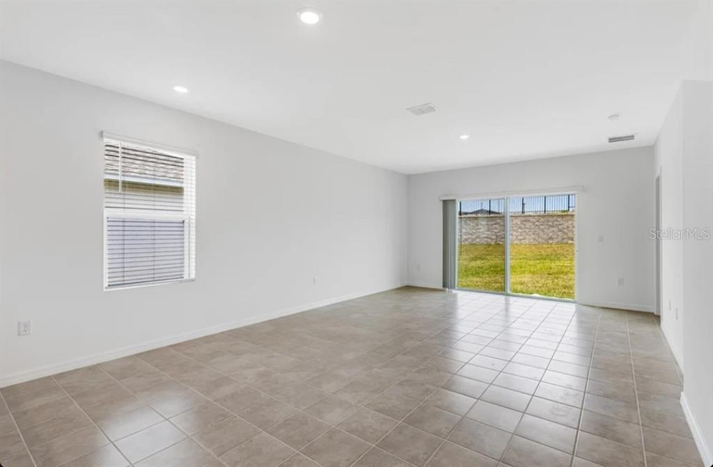 An empty room with light-colored walls, tile flooring, a window, and sliding glass doors — 9336 CHISWELL TRAIL, PALMETTO, FL