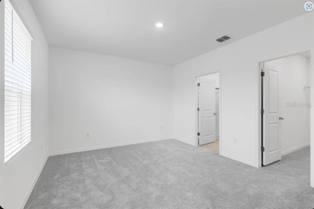 An empty bedroom with white walls, gray carpet, a window with blinds, and two doors — 9336 CHISWELL TRAIL, PALMETTO, FL