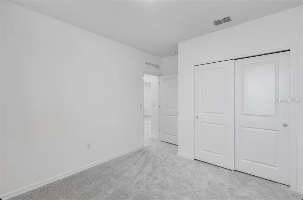 A bedroom with white walls, gray carpet, and a white sliding-door closet — 9336 CHISWELL TRAIL, PALMETTO, FL