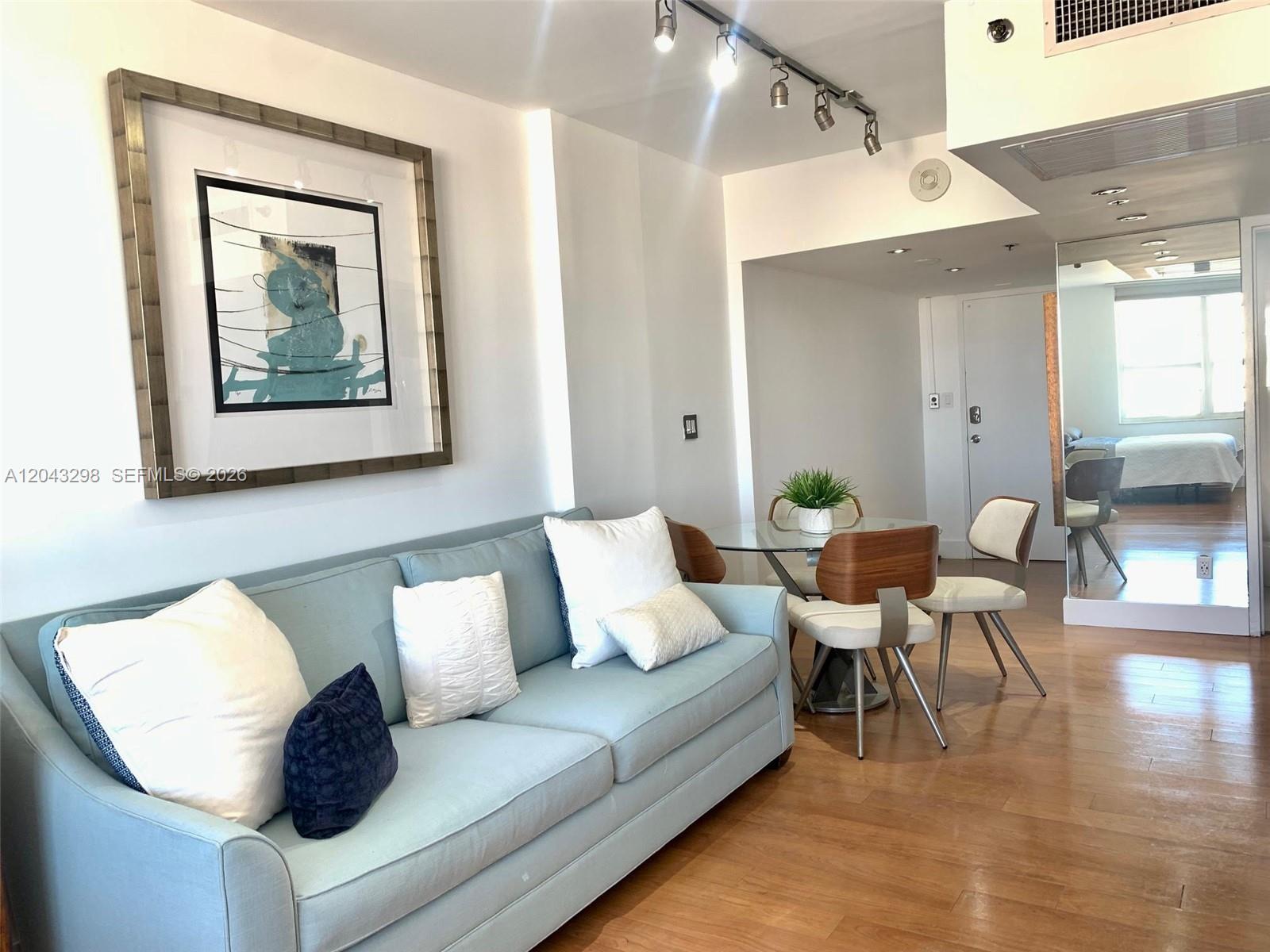 A living room features a light blue sofa, a glass dining table, and hardwood floors — 100 Lincoln Rd # 1514A, Miami Beach FL 33139, MIAMI BEACH, FL