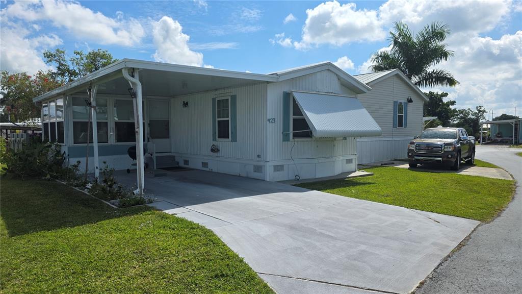 A white mobile home features a carport, a concrete driveway, and a metal window awning — 123 6TH STREET, PUNTA GORDA, FL