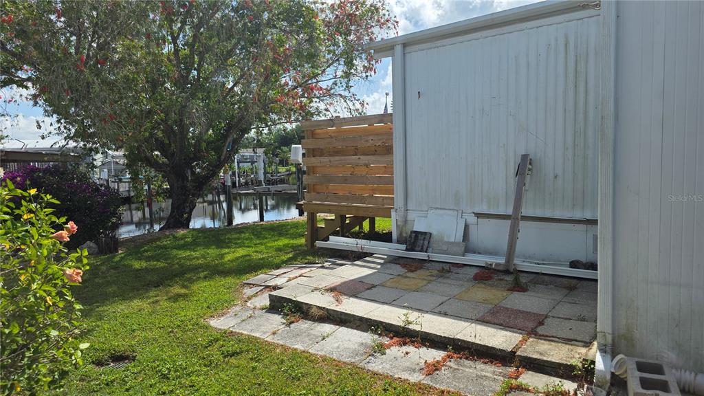 A paved patio sits beside a white mobile home with a wooden privacy screen nearby — 123 6TH STREET, PUNTA GORDA, FL