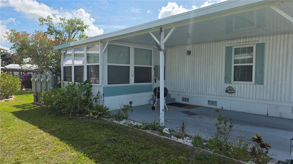 A mobile home exterior features a covered carport, a screened-in porch, and a grassy yard — 123 6TH STREET, PUNTA GORDA, FL