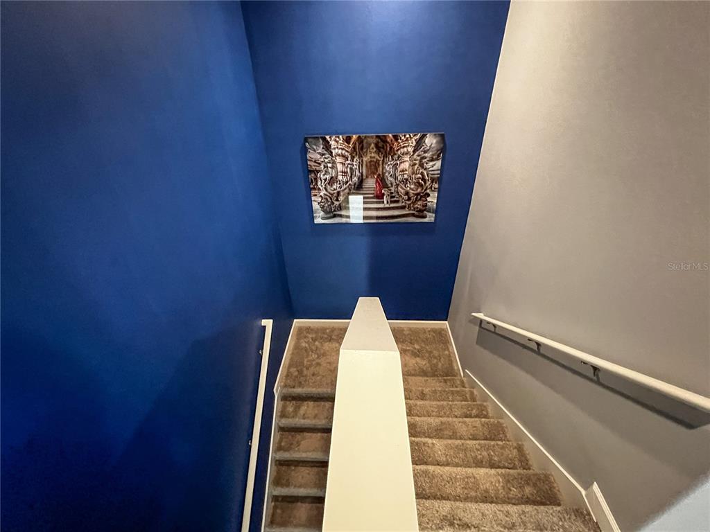 A carpeted staircase features a blue accent wall with a framed picture and white railings — 8984 AZALEA SANDS LANE UNIT 8984, DAVENPORT, FL