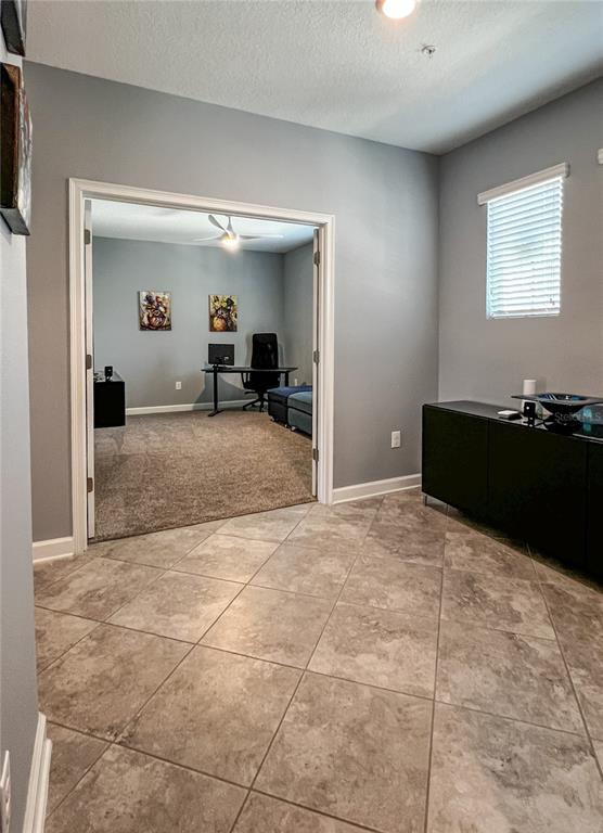 A room with tile flooring leads through double doors into a carpeted home office — 8984 AZALEA SANDS LANE UNIT 8984, DAVENPORT, FL