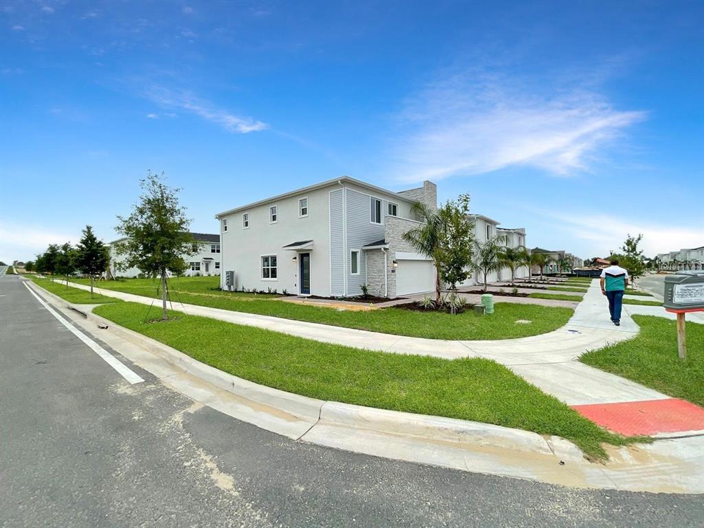 A light-colored two-story townhouse with a stone facade and attached garage sits on a corner — 218 NINE IRON DRIVE, DAVENPORT, FL