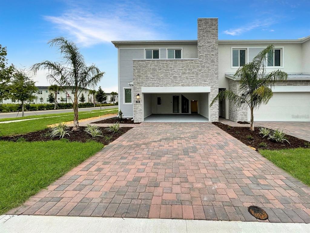 A two-story townhome with a stone facade, a covered carport, and a paved driveway — 218 NINE IRON DRIVE, DAVENPORT, FL