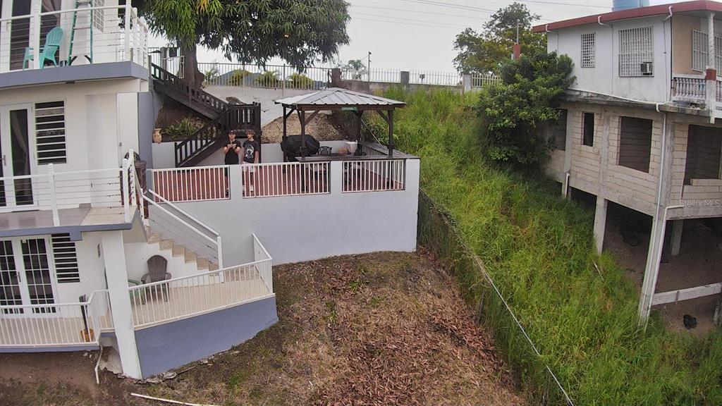 An elevated deck with a gazebo sits between a multi-story house and a grassy slope — Carr. 115 SECTOR SOTO ROAD, RINCON, PR