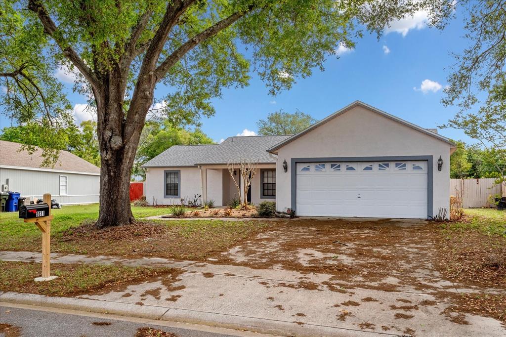 A single-story house with a white stucco exterior, a two-car garage, and a large tree — 5031 WATER WHEEL COURT, OCOEE, FL