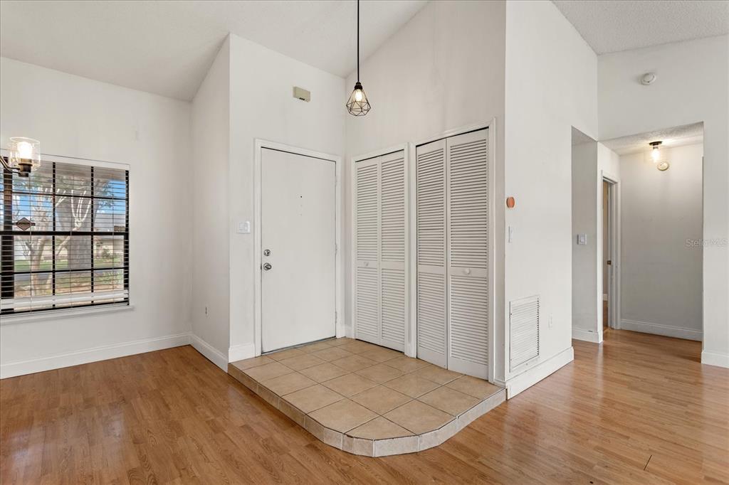 An entryway with a tiled floor, white louvered closet doors, and light wood flooring — 5031 WATER WHEEL COURT, OCOEE, FL
