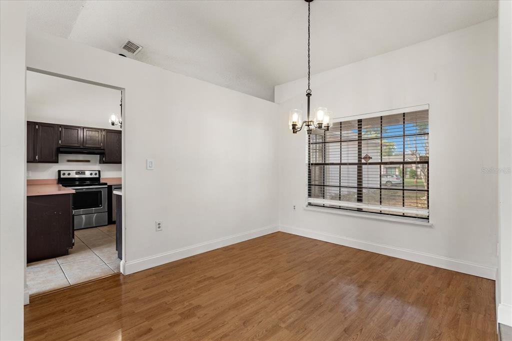 A dining room with wood flooring, a chandelier, and a view into the kitchen — 5031 WATER WHEEL COURT, OCOEE, FL