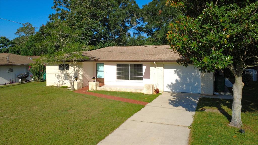 A single-story brick house with a white garage, front porch, and a concrete driveway — 609 GOODYEAR AVENUE, INVERNESS, FL