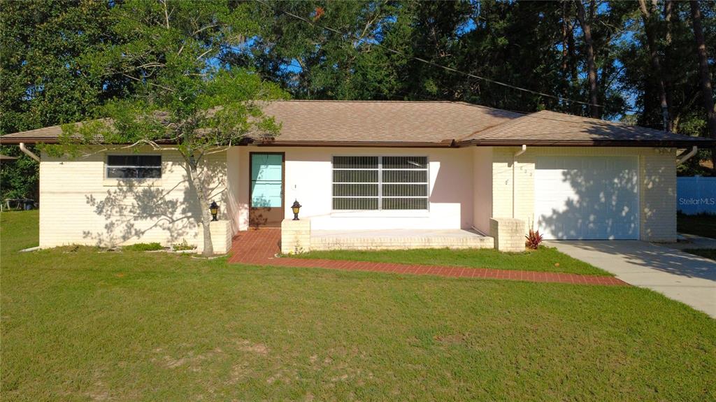 A single-story brick house with a front porch, a garage, and a red brick walkway — 609 GOODYEAR AVENUE, INVERNESS, FL