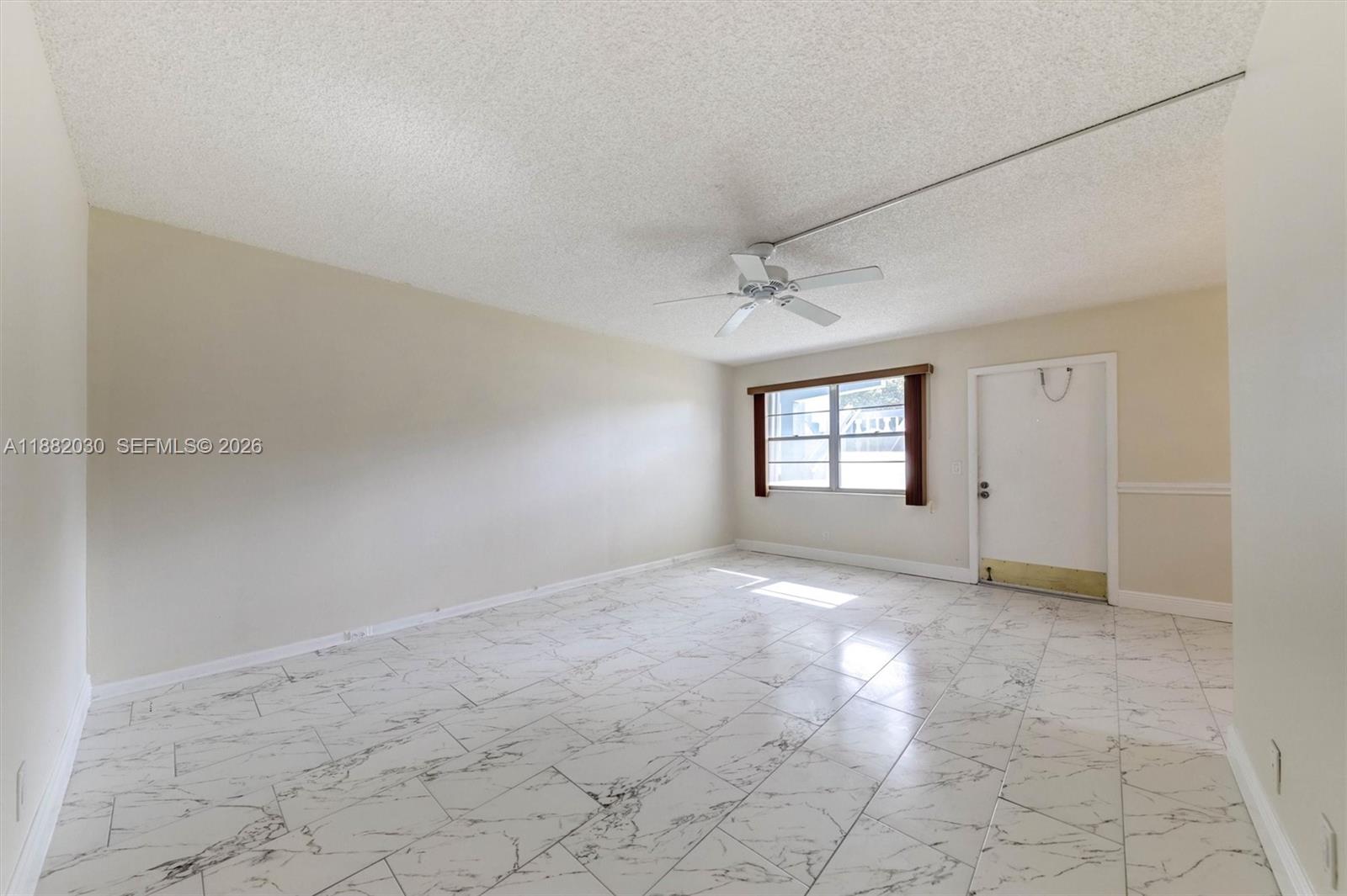 An empty room features white marble-look tile flooring, a ceiling fan, and a single window — 36 Islewood B # 36, Deerfield Beach FL 33442, DEERFIELD BEACH, FL