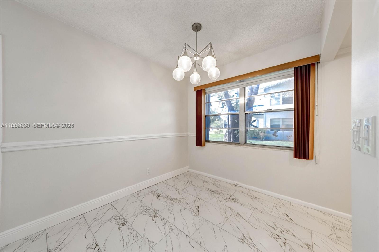 A dining room features white walls with chair rail molding, marble-look tile flooring, and a chandelier — 36 Islewood B # 36, Deerfield Beach FL 33442, DEERFIELD BEACH, FL