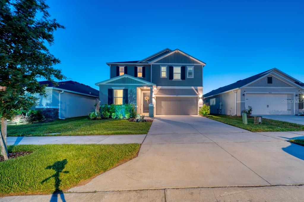 A two-story suburban house with a gray exterior, a two-car garage, and a concrete driveway — 880 ALVANLEY COURT, DAVENPORT, FL