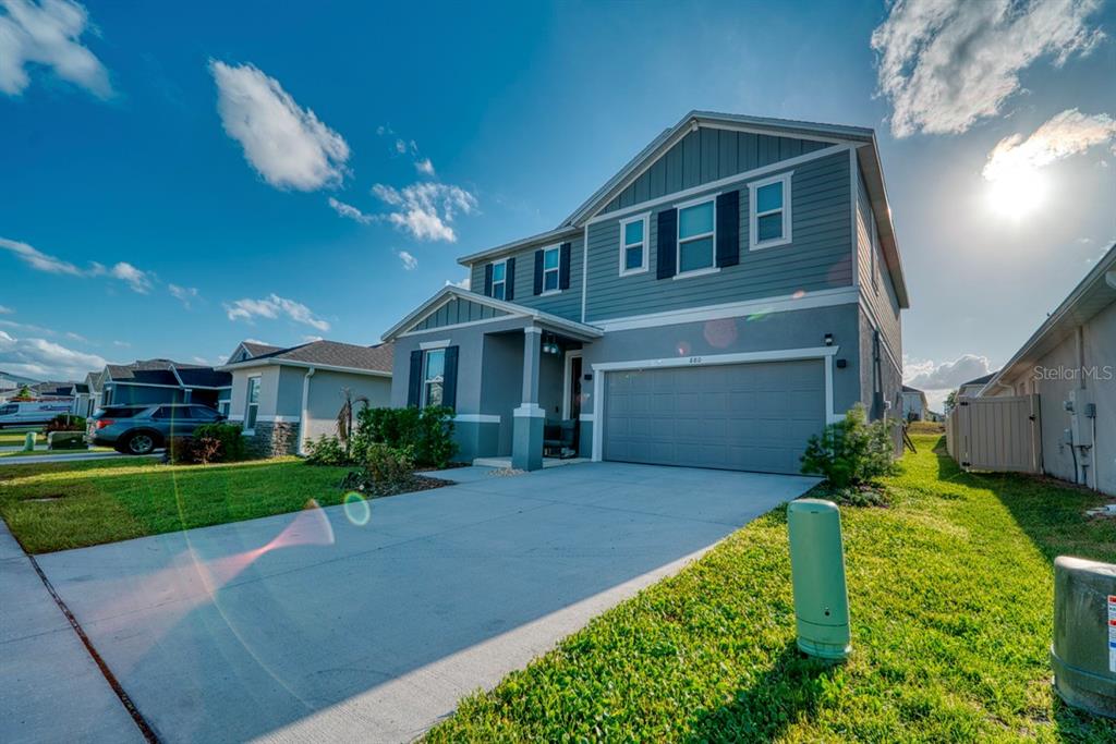 A two-story house with blue siding, a gray garage door, and a concrete driveway — 880 ALVANLEY COURT, DAVENPORT, FL