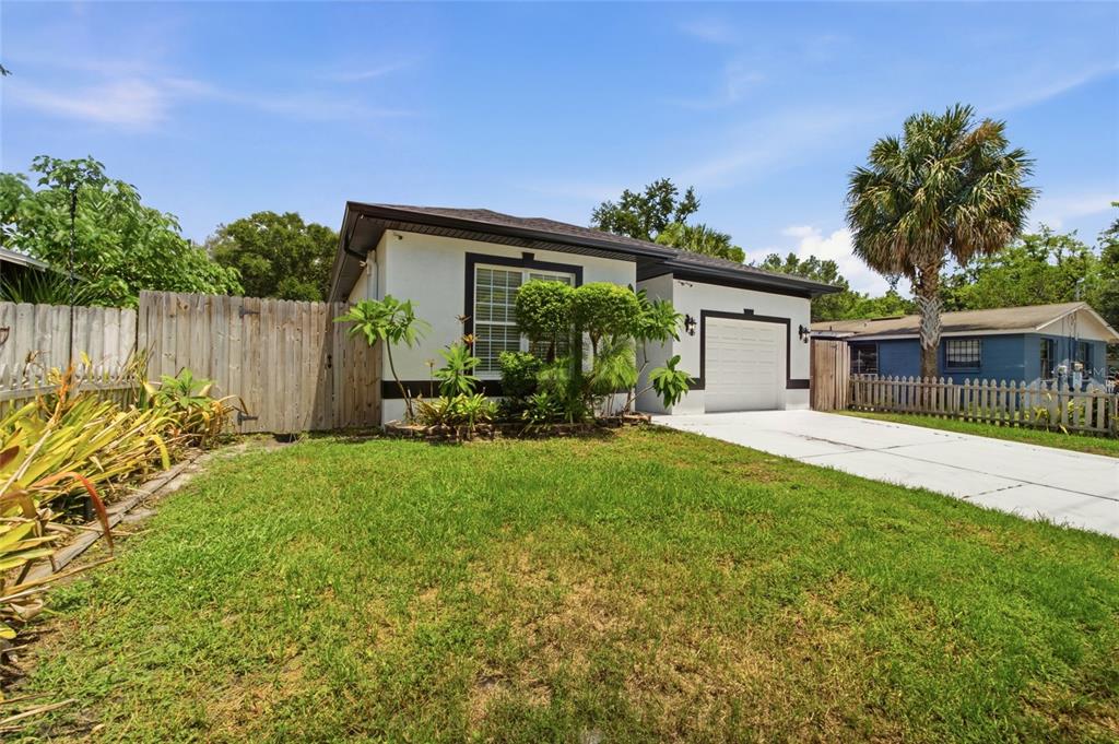 A single-story house with a white exterior, a garage, and a front lawn — 8205 N 12TH STREET, TAMPA, FL