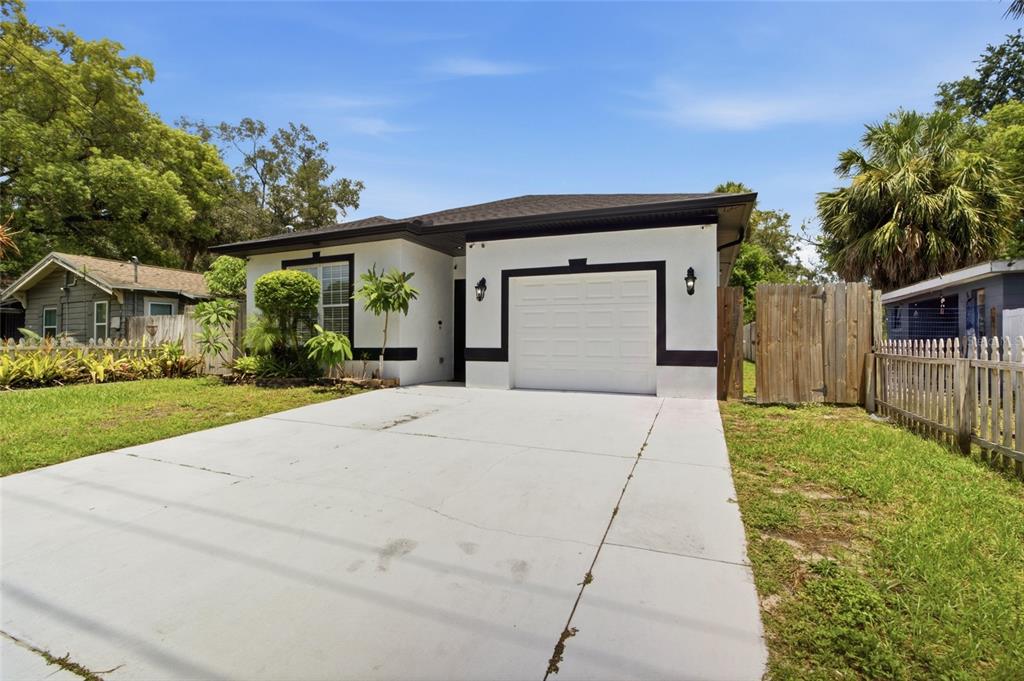 A single-story house with a white exterior, black trim, and a concrete driveway — 8205 N 12TH STREET, TAMPA, FL
