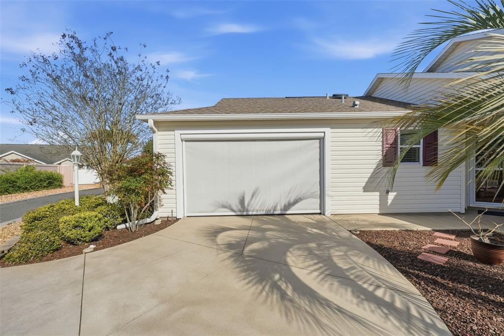 A beige house exterior features a garage with a retractable screen door and a driveway — 2311 CRESTVIEW STREET, THE VILLAGES, FL