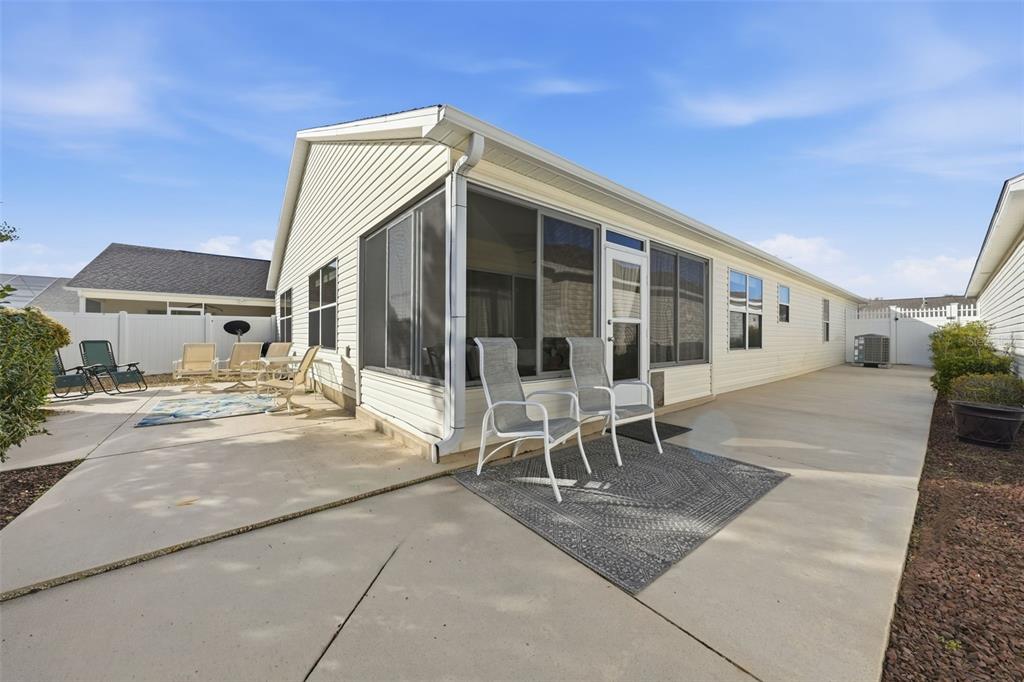 A beige house with a screened-in porch and a concrete patio in the backyard — 2311 CRESTVIEW STREET, THE VILLAGES, FL