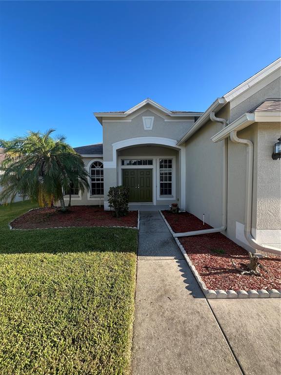 The exterior of a single-story house features a concrete walkway leading to a double-door entrance — 22736 BELTREES COURT, LAND O LAKES, FL