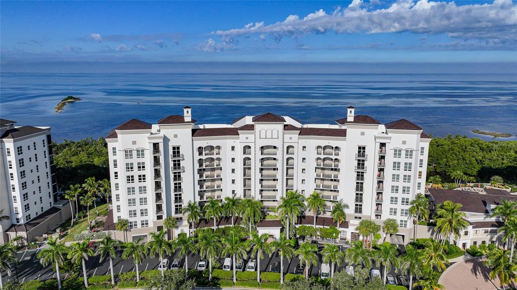 An aerial view shows a large, multi-story white resort building situated along a coastal shoreline — 3329 SUNSET KEY CIRCLE UNIT 308, PUNTA GORDA, FL