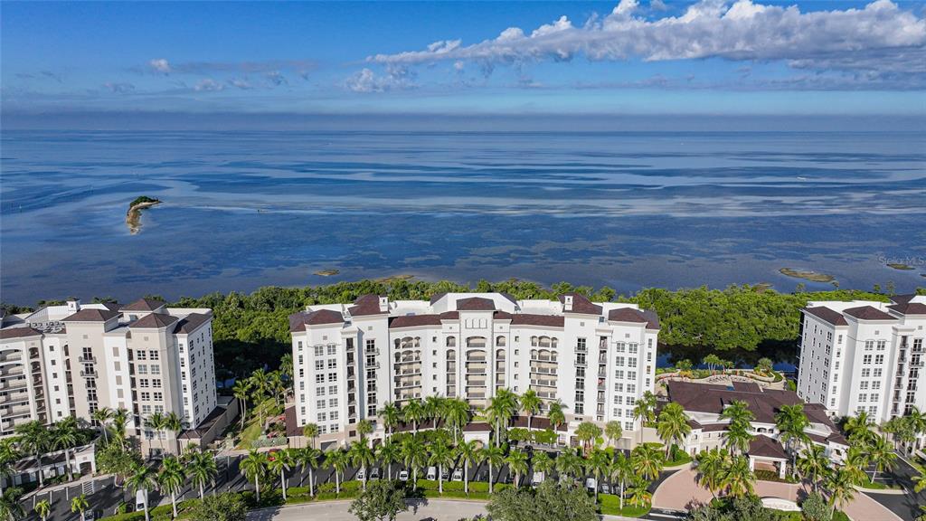 An aerial view shows a large multi-story apartment complex situated along a coastal waterfront — 3329 SUNSET KEY CIRCLE UNIT 308, PUNTA GORDA, FL