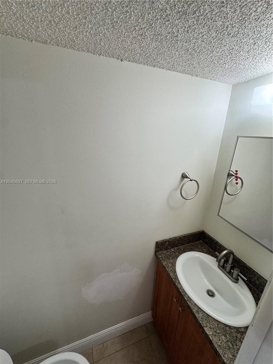 A small bathroom features a vanity with a granite countertop and a wall-mounted towel ring — 421 Swallow Dr # 10, Miami Springs FL 33166, MIAMI SPRINGS, FL
