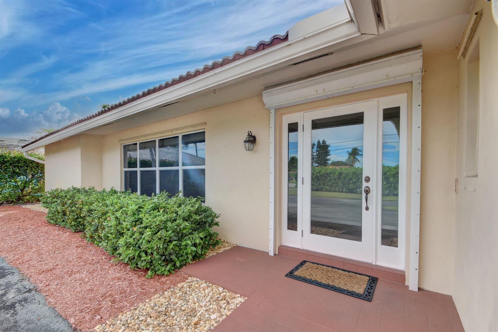 A beige house exterior features a white front door with sidelights and a tiled porch — 1753 W Terrace Drive, FL 33460, FL