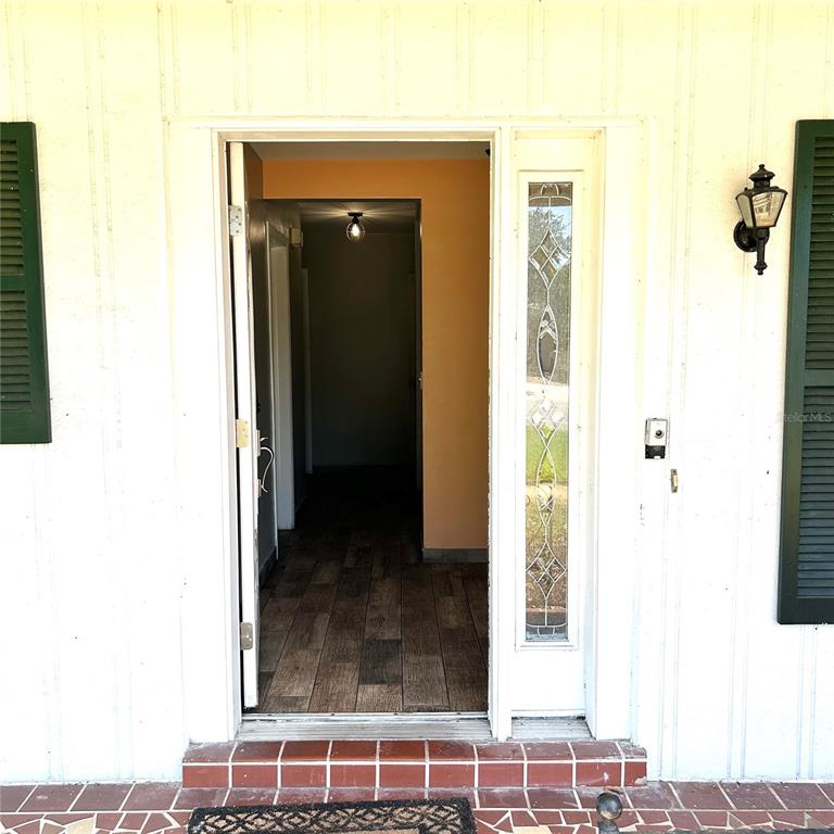A front door with a decorative glass sidelight opens into a home with wood-look flooring — 2152 GREENBRIAR BOULEVARD, CLEARWATER, FL