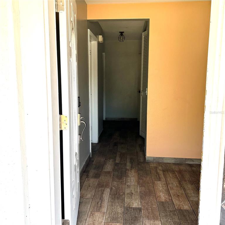 An entryway with wood-look tile flooring leads to a hallway with a light fixture — 2152 GREENBRIAR BOULEVARD, CLEARWATER, FL