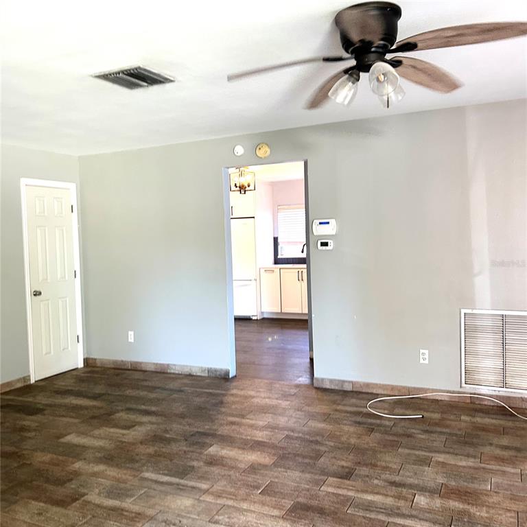 A living room with wood-look tile flooring, a ceiling fan, and a doorway to a kitchen — 2152 GREENBRIAR BOULEVARD, CLEARWATER, FL