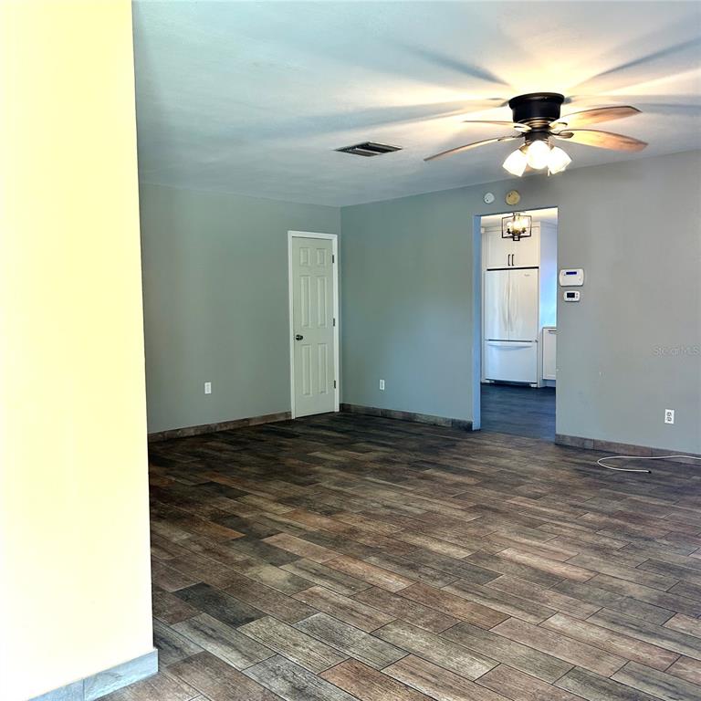 A living area with wood-look tile flooring, gray walls, a ceiling fan, and a doorway — 2152 GREENBRIAR BOULEVARD, CLEARWATER, FL